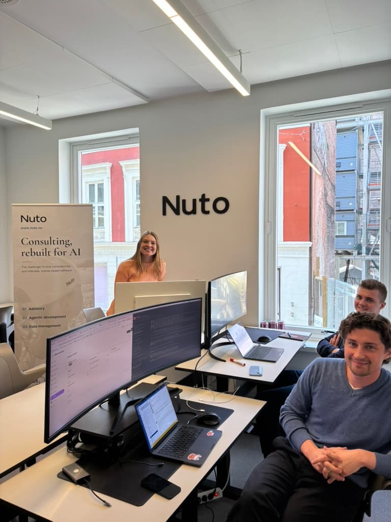 Nuto-teamet på kontoret, med Nuto-logoen på veggen